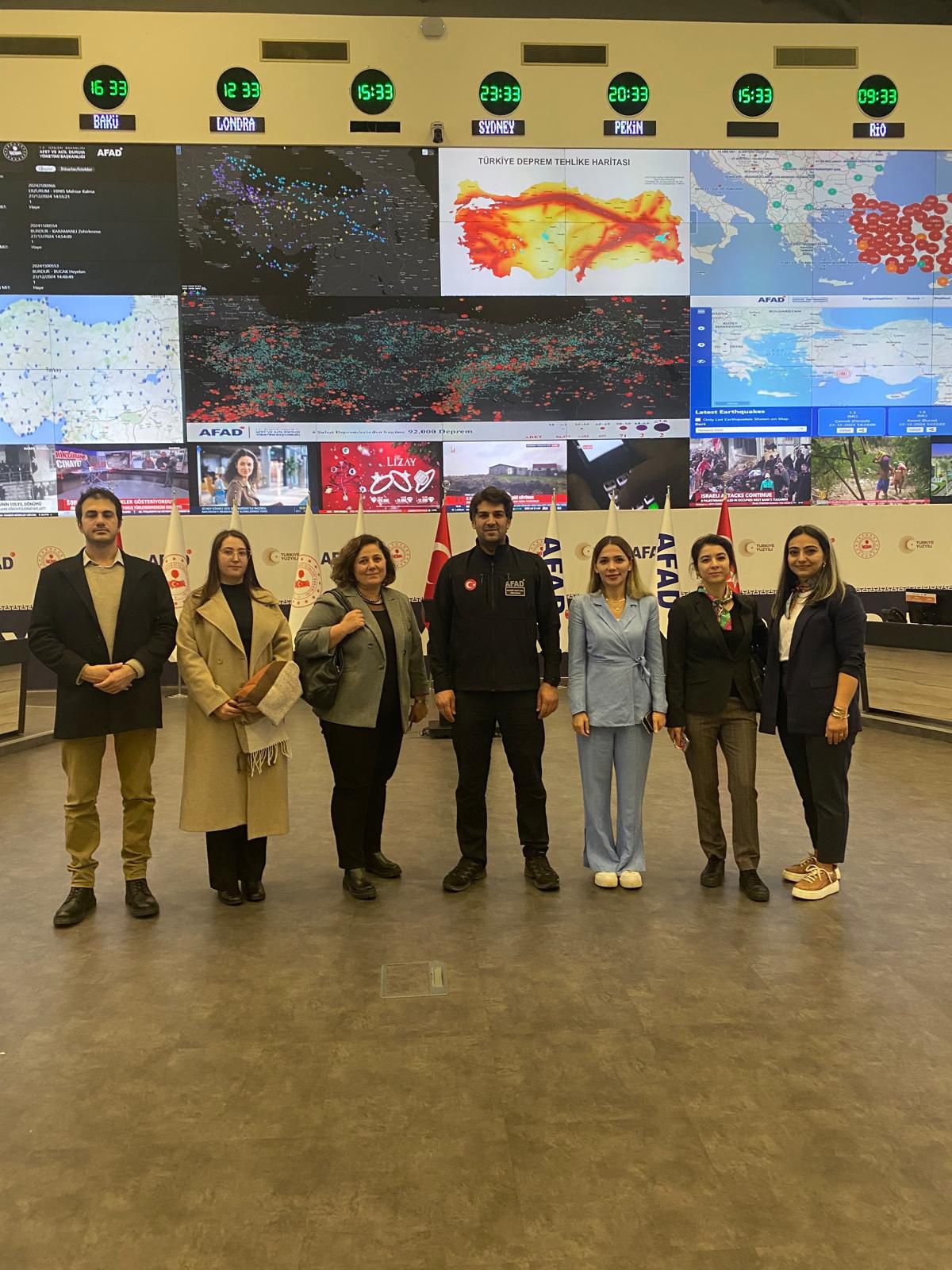 ASBÜ Yabancı Diller Fakültesi Hocaları, öğrencileri ve Dış İlişkiler Daire Başkanı Muhammet Maruf Yaman AFAD merkezinde izleme takip ekranları önünde fotoğraf çektiriyorlar. 