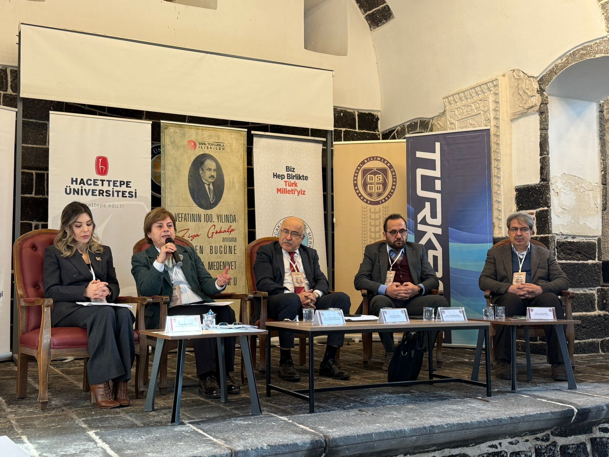 Paneldeki dört konuşmacı oturarak konuşmalarını gerçekleştiriyor