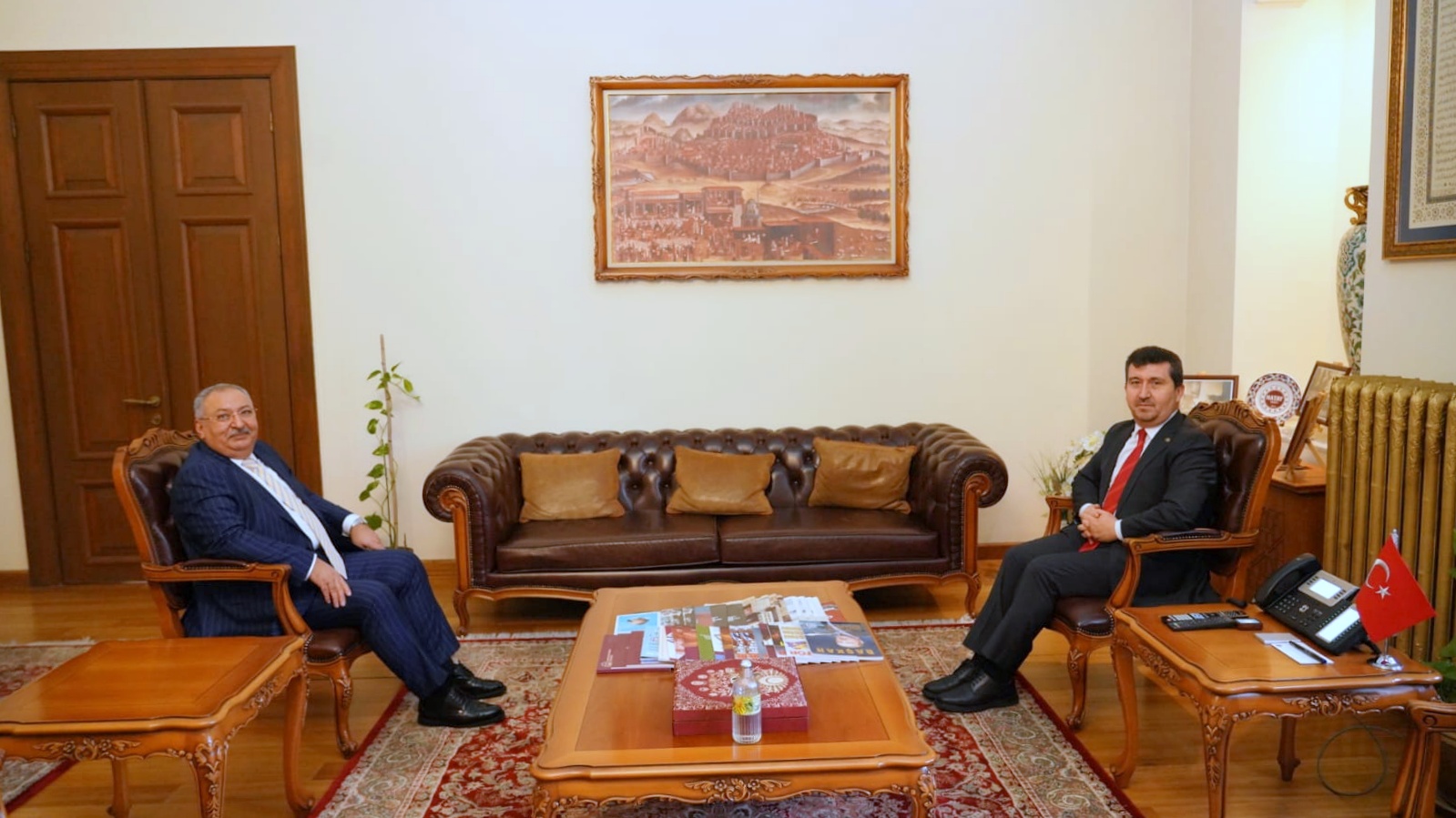 ASBÜ Rektörü Prof. Dr. Musa Kazım Arıcan, Metin Kıratlı ile makam odasında karşılıklı tekli koltuklarda oturuyor