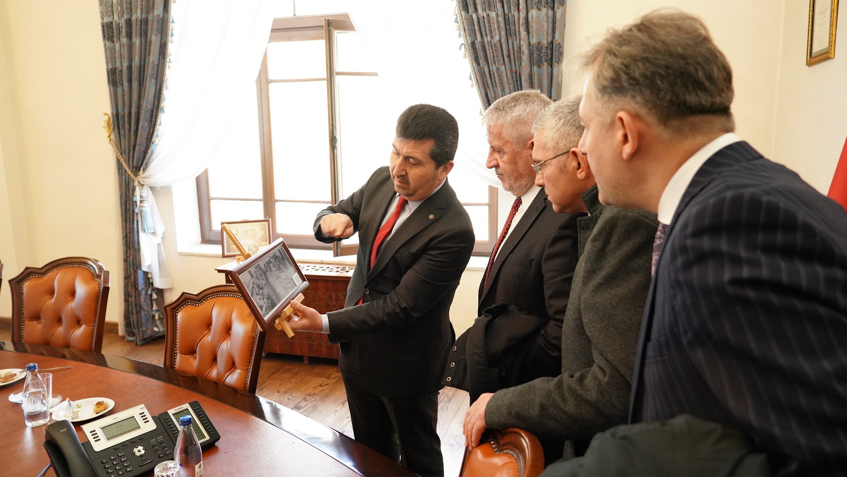 ASBÜ Rektörü Prof. Dr. Musa Kazım Arıcan ASBÜ senato salonunda aynı salonda çekilmiş tarihi fotoğrafları konuklar ile inceliyorlar.