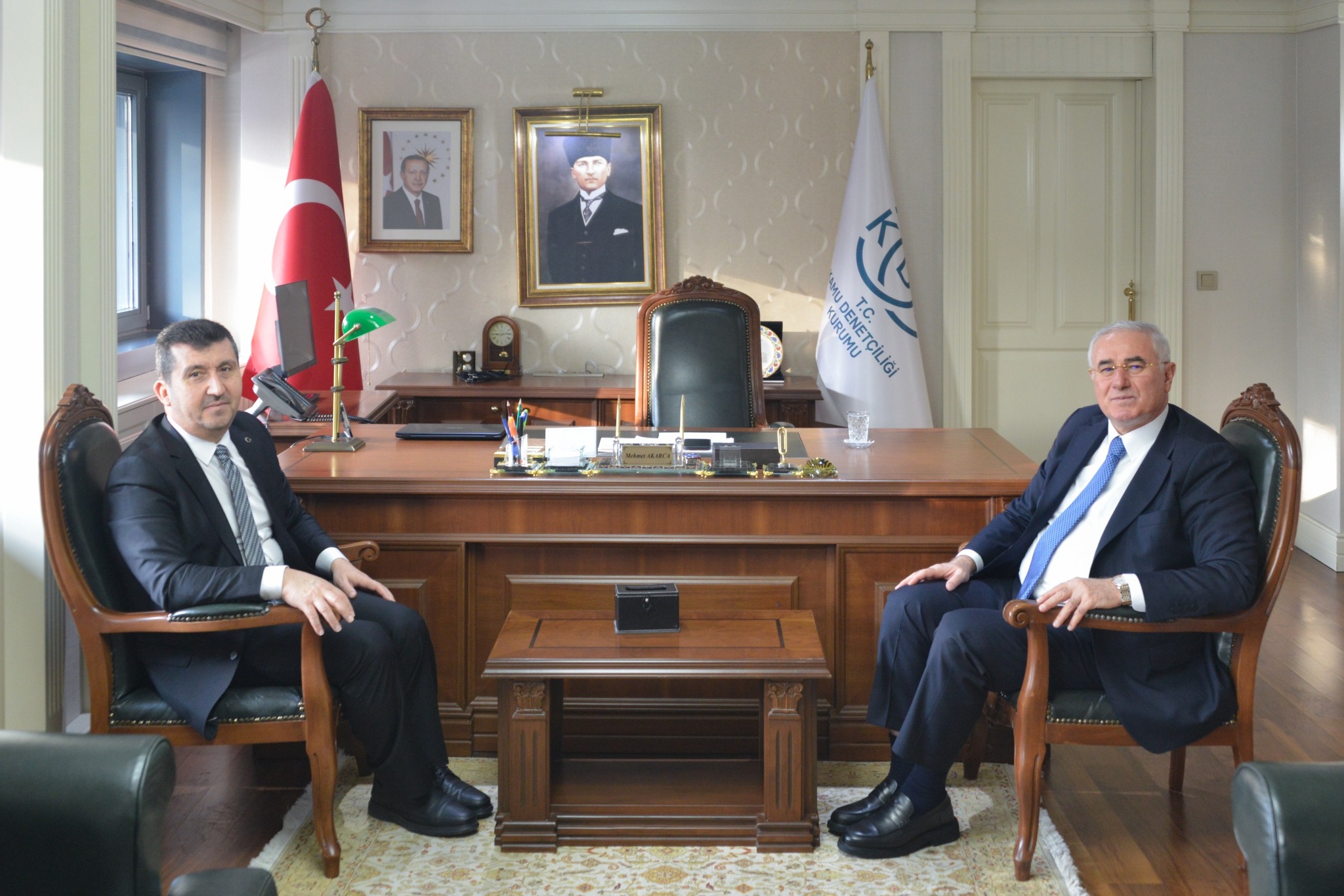 rektör hocamız ve mehmet akarca oturarak poz verdiler