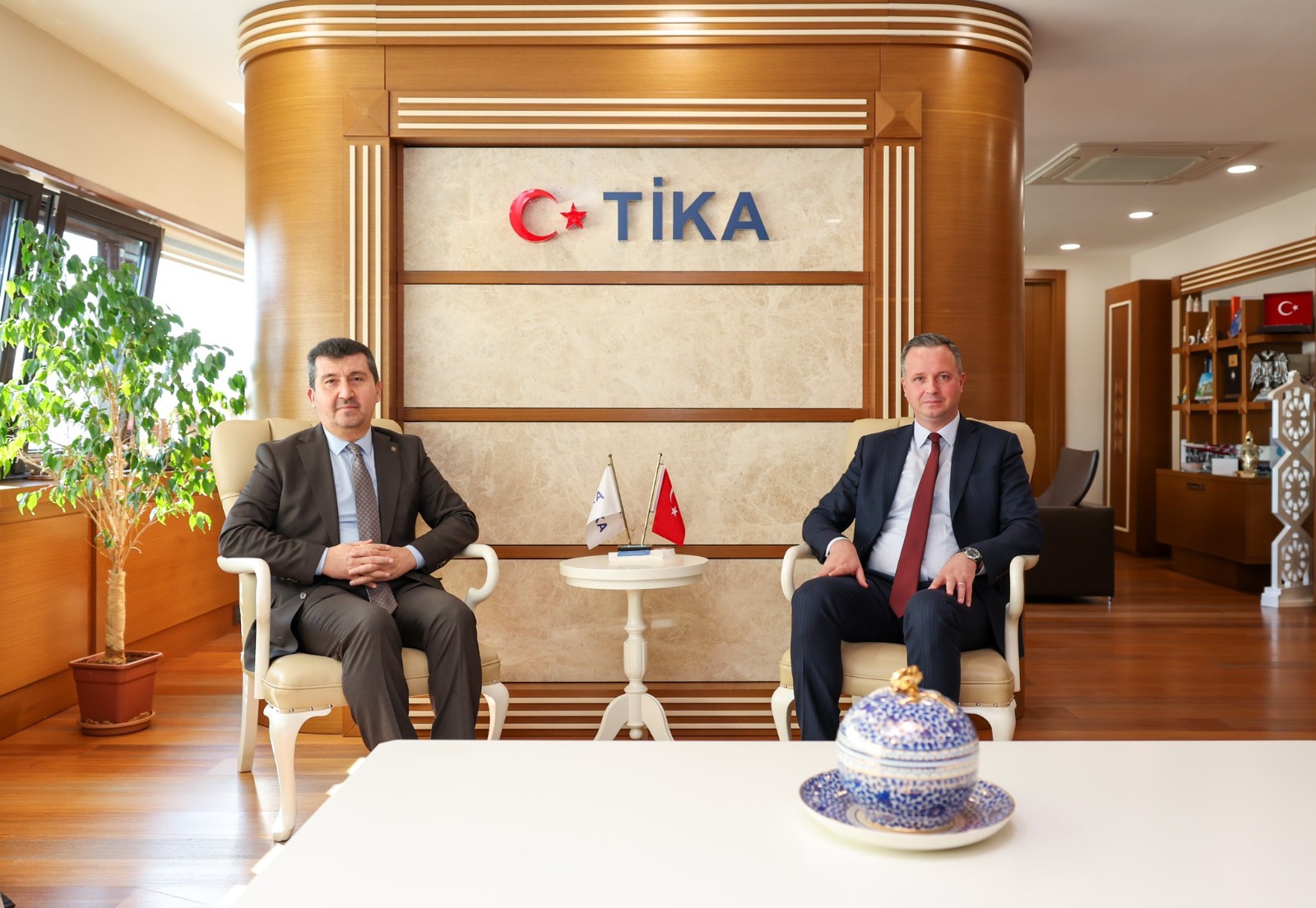 ASBÜ Rektörü Prof. Dr. Musa Kazım Arıcan ve TİKA Başkanı Serkan Kayalar makam odasında fotoğraf çektiriyorlar.