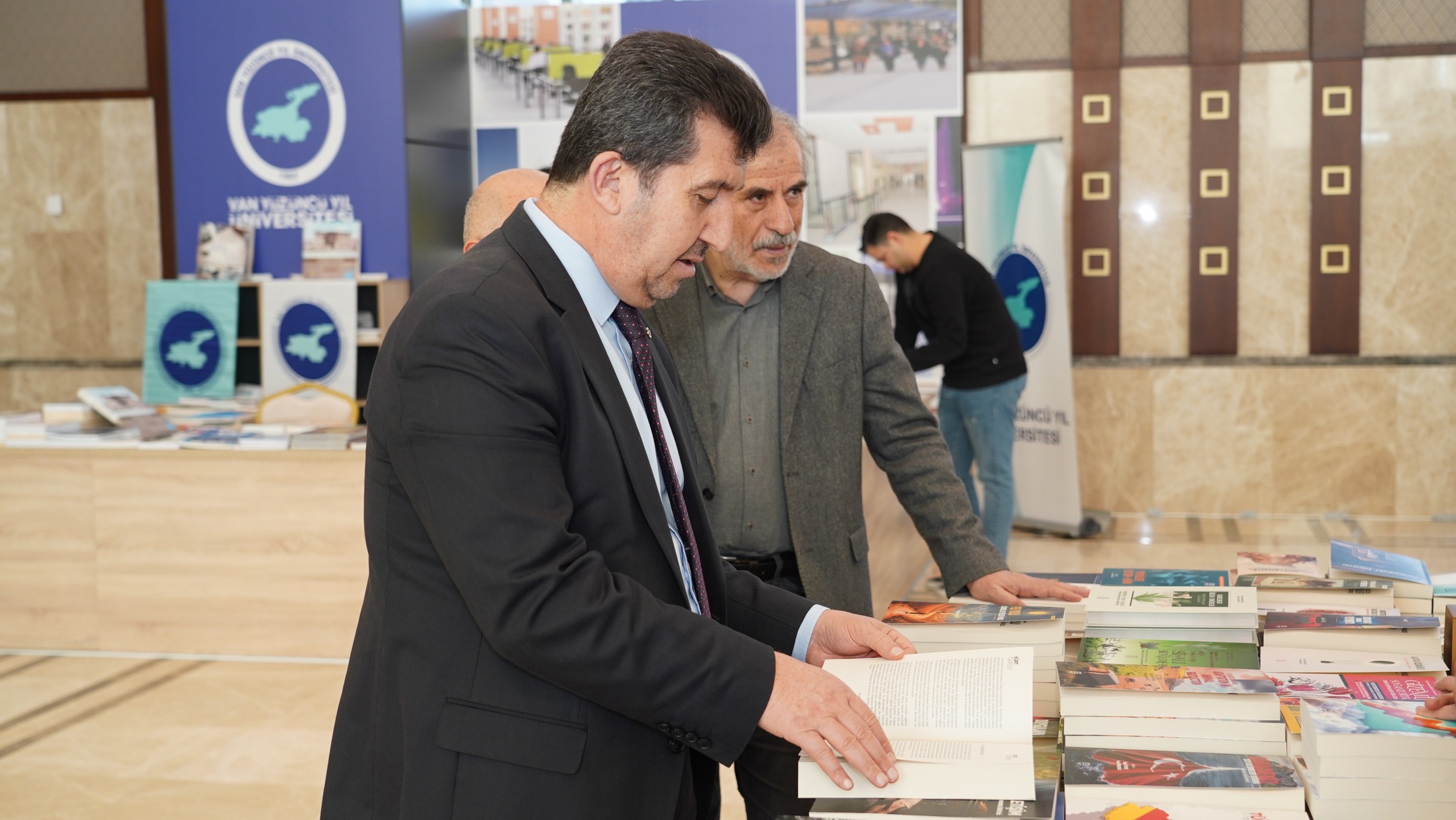 ASBÜ Rektörü Prof. Dr. Musa Kazım ARICAN ve ASBÜ Kütüphane Daire Başkanı Osman KAYAER fuardaki standlarda kitapları inceliyorlar.