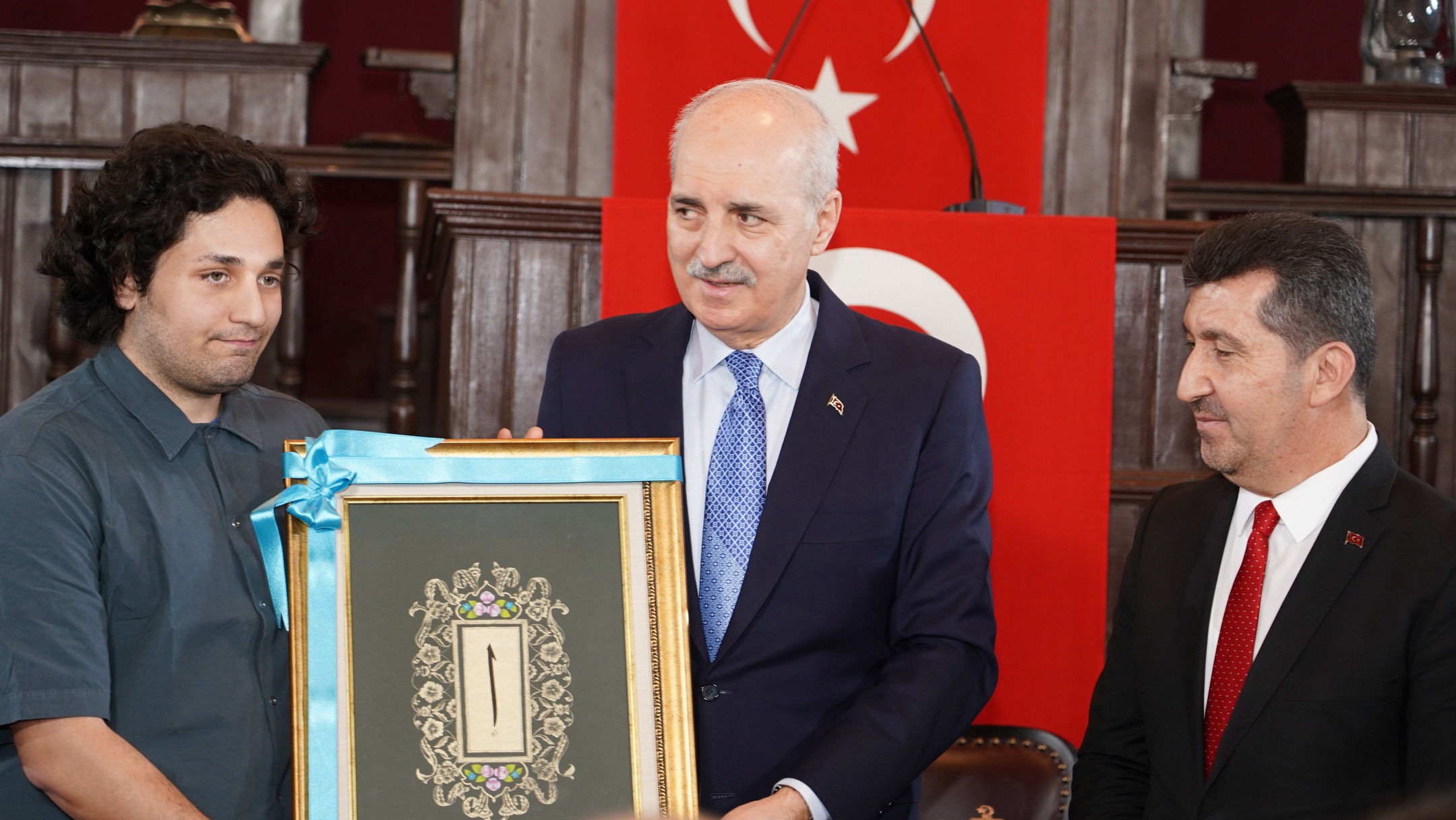 Türkiye Büyük Millet Meclisi Başkanı  Numan Kurtulmuş ve ASBÜ Rektörü  Prof. Dr. Musa Kazım Arıcan öğrenciye hediye takdim ediyorlar.
